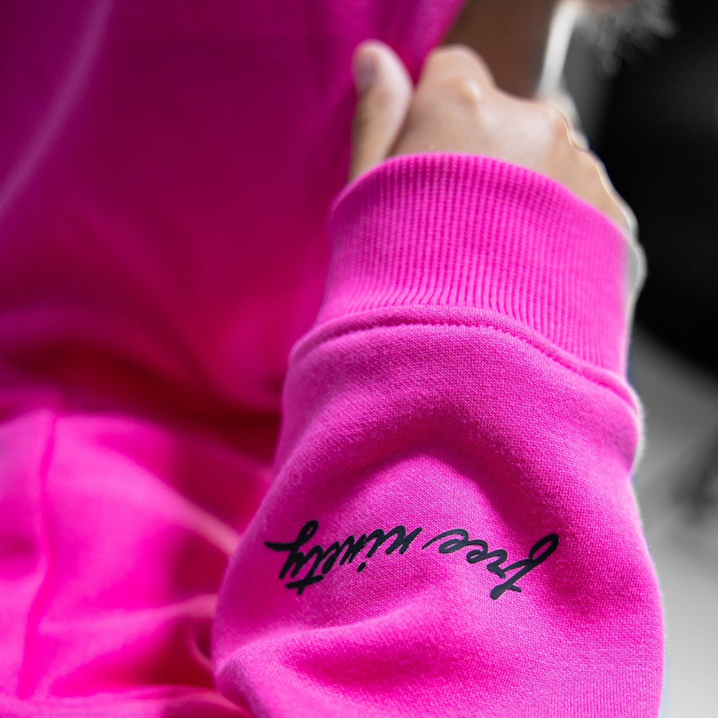 Close-up of a pink sweatshirt with 'free ninety' text on the sleeve.