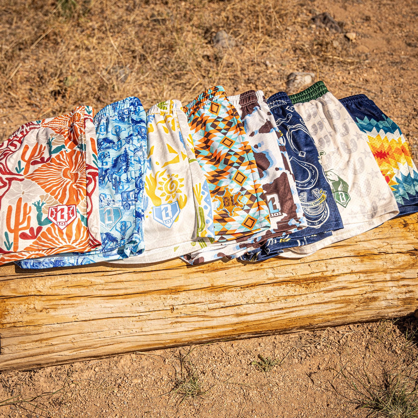 Eight patterned shorts on a wooden log with a natural outdoor background