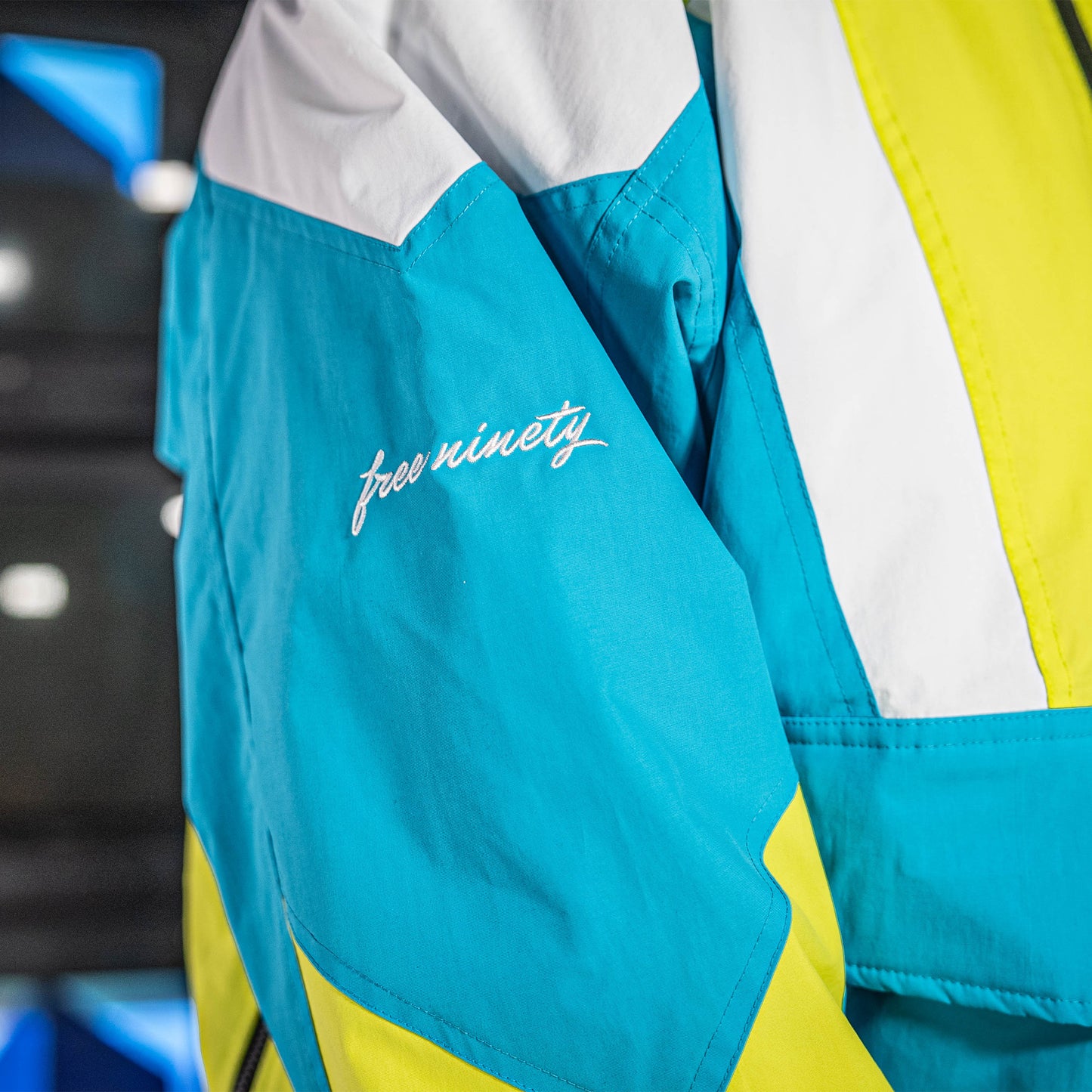 Blue, yellow and white jacket with 'free ninety' branding on a blurred background