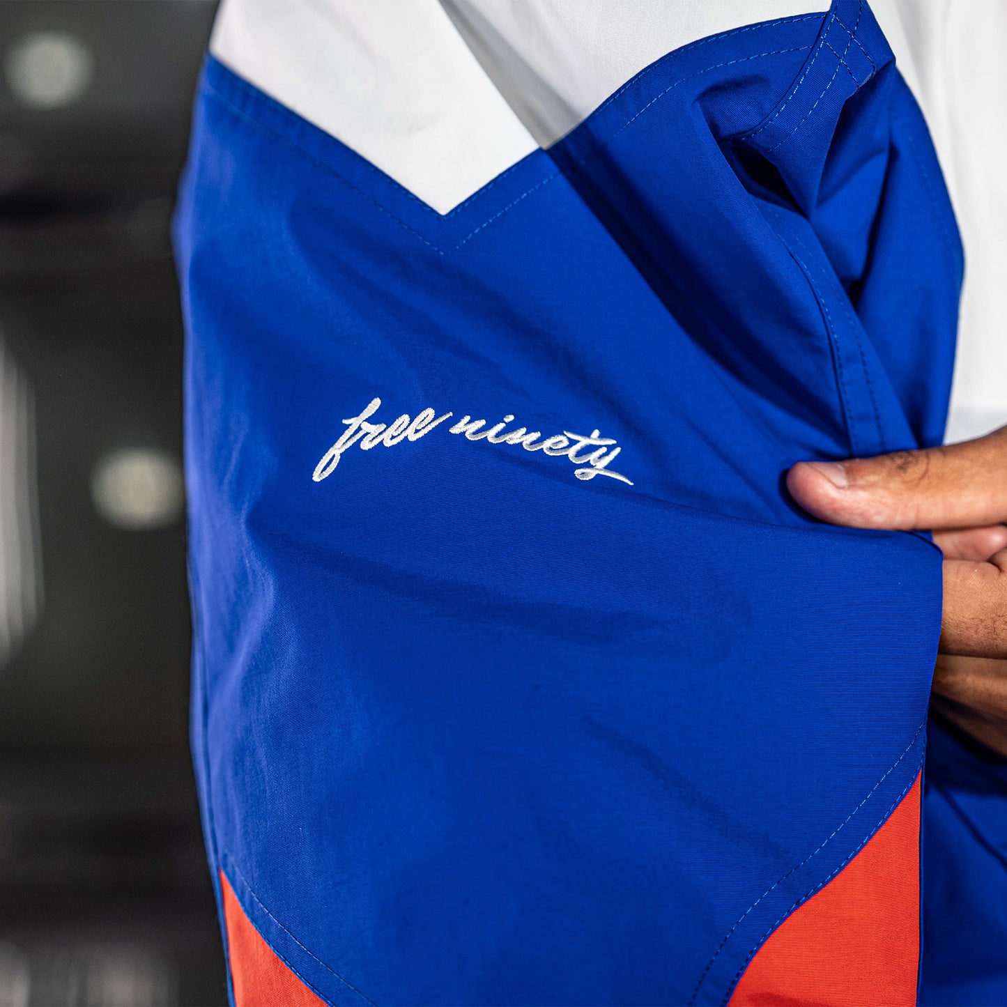 Blue, red and white jacket with 'free ninety' branding on a blurred background