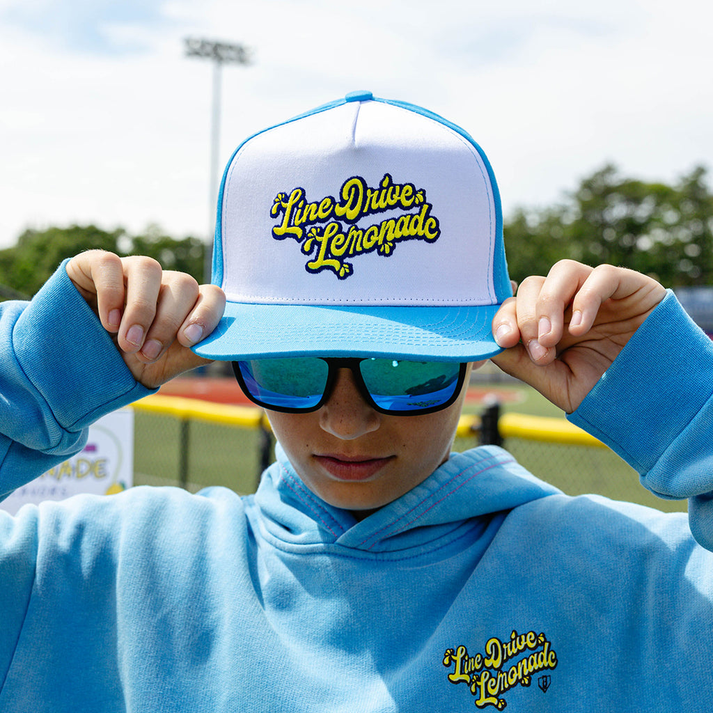 Adult model wearing blue hat with "Lemonade Off Field" design