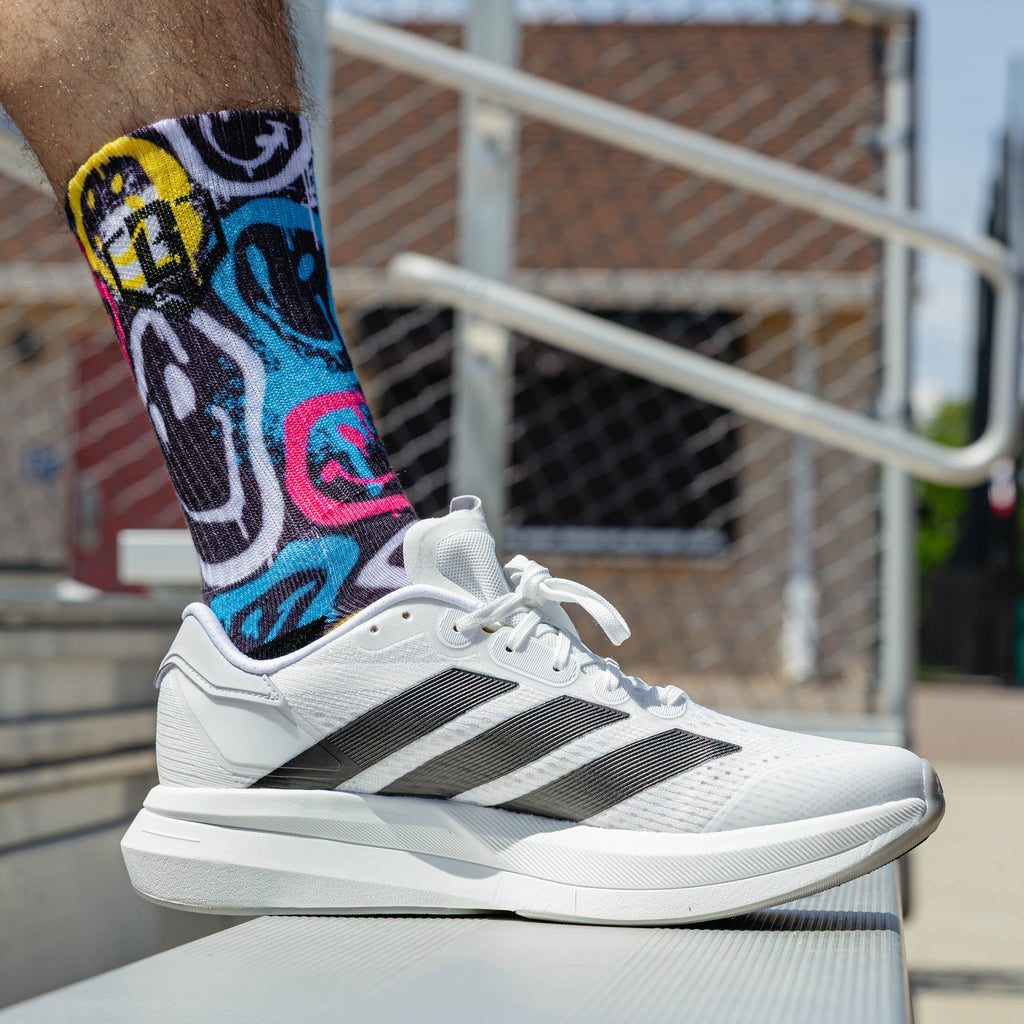 Adult model wearing multi-color socks with "Smiley Slugger Performance  3-Pack" design