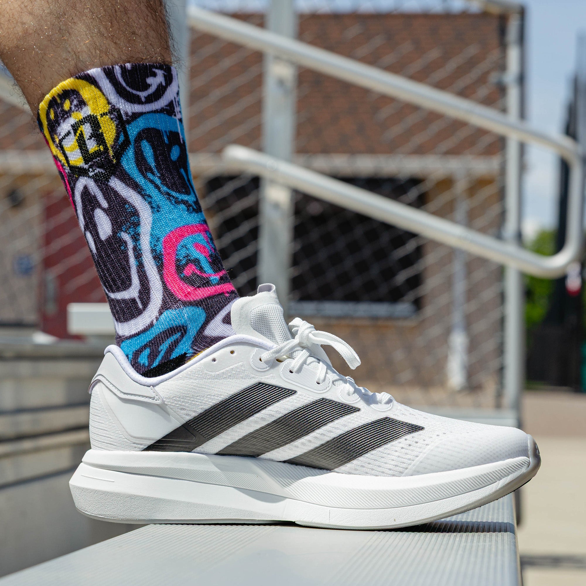 Adult model wearing multi-color socks with "Smiley Slugger Performance  3-Pack" design