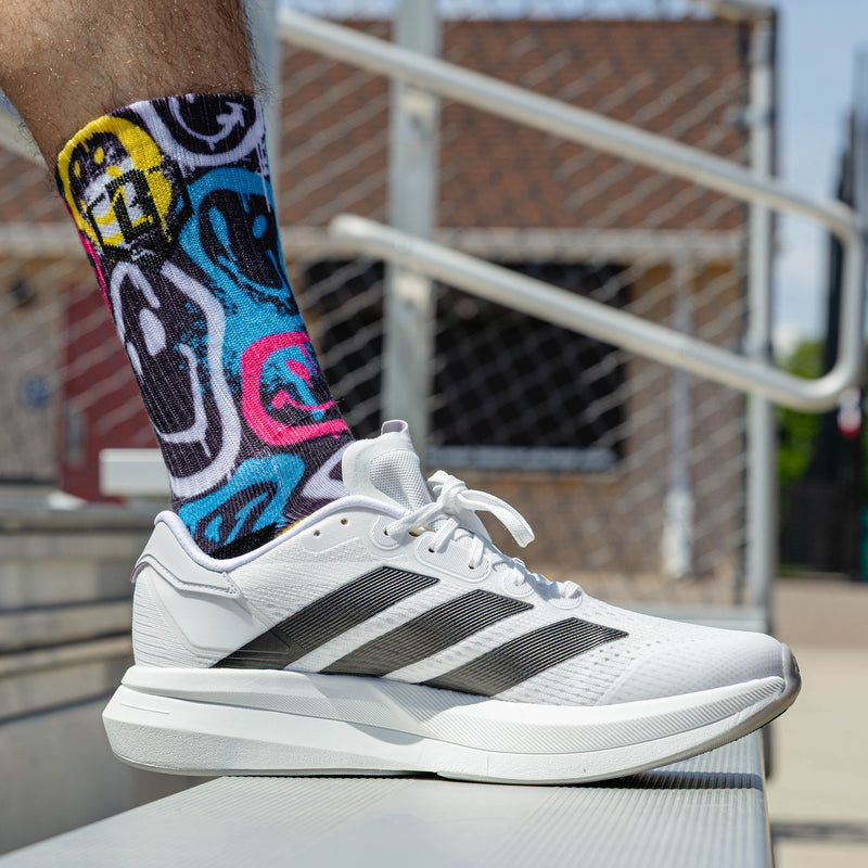 Adult model wearing multi-color socks with "Smiley Slugger Performance  3-Pack" design