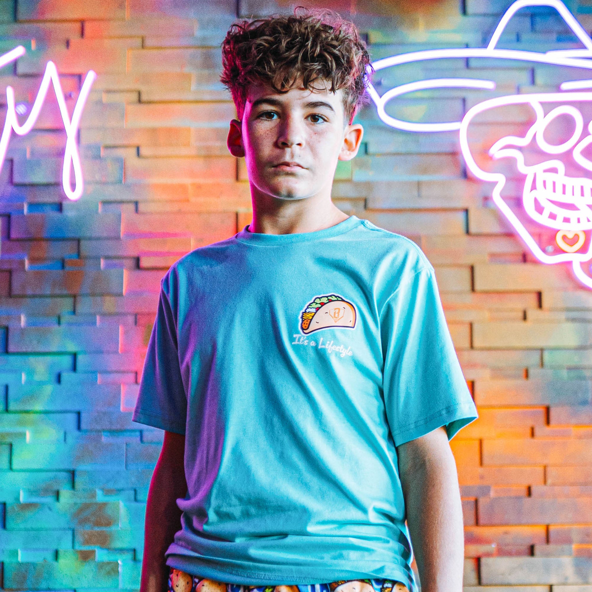 Person wearing teal t-shirt with a taco graphic design and 'It's a lifestyle' text