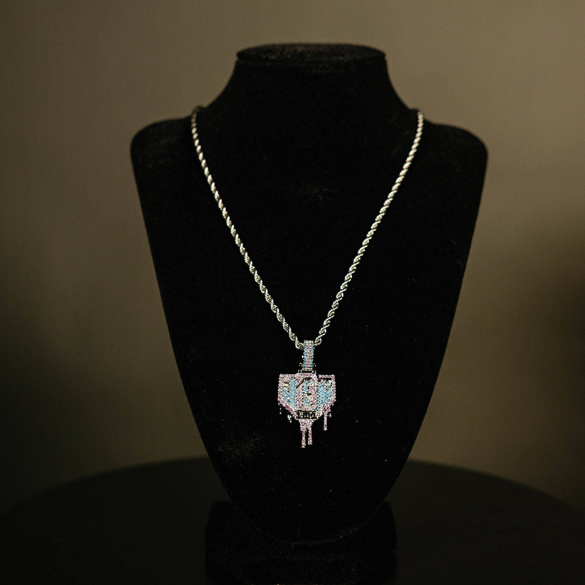 White Gold BL101 Drip Plate necklace hanging on a display stand against a black background