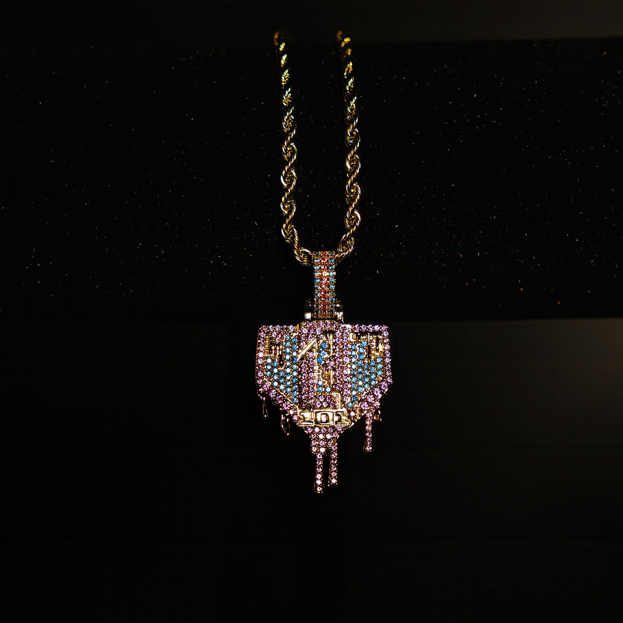 Yellow Gold BL101 Drip Plate necklace hanging on a display stand against a black background