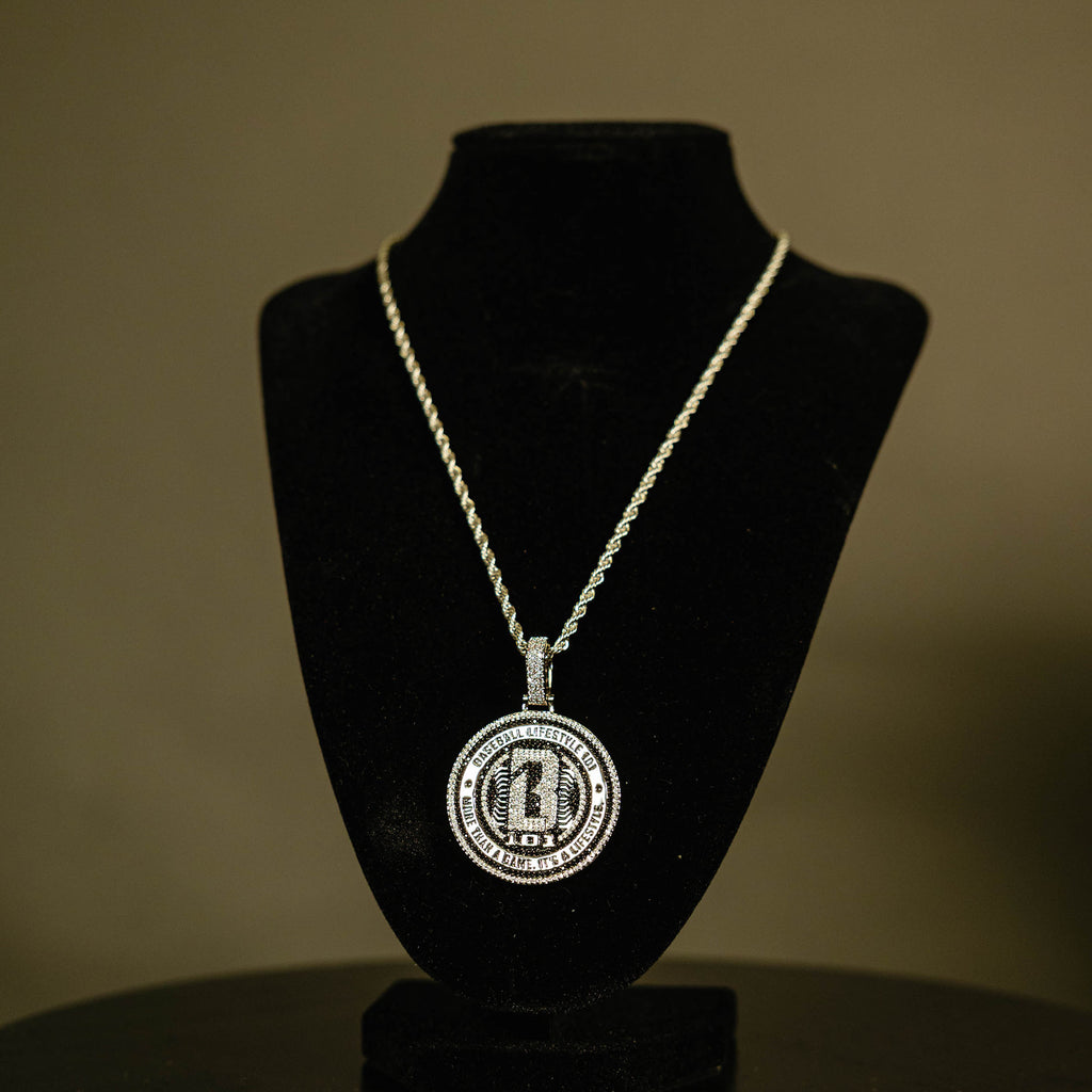 White Gold BL101 Medallion necklace hanging on a display stand against a black background