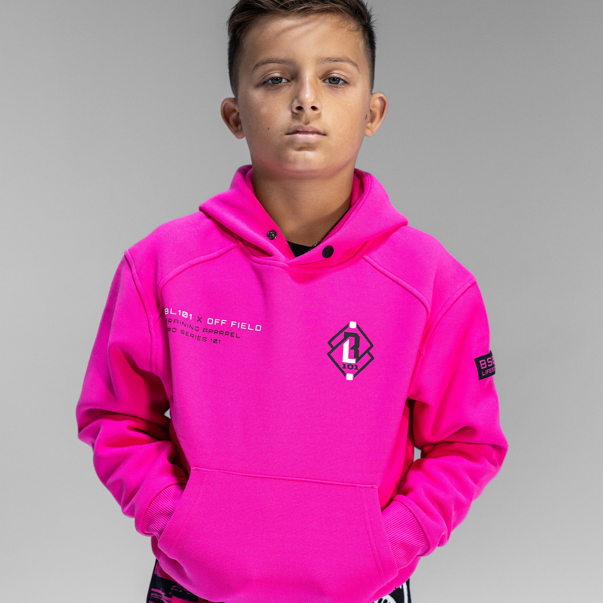 Child wearing pink hoodie with 'BL101 X OFF FIELD' logo on chest 