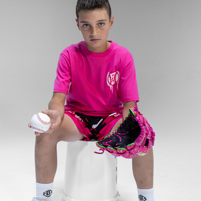 Child in pink t-shirt with a white BL101 logo  with baseball and glove on a gray background