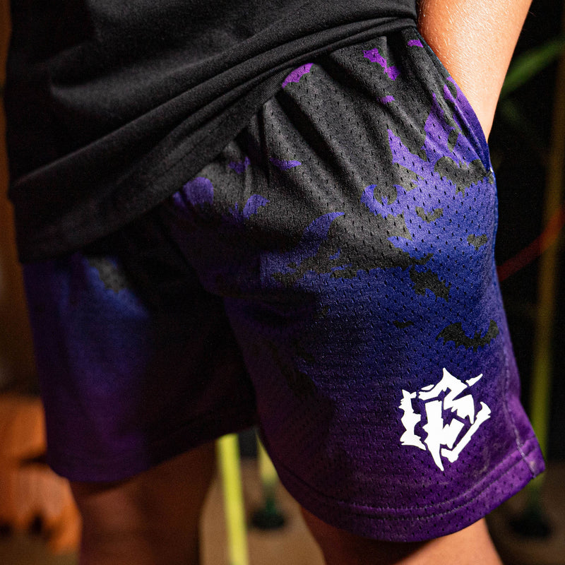 Person wearing purple and black shorts with a white BL logo on a blurred background