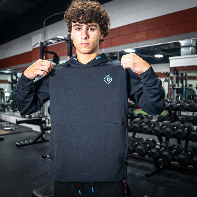 Person wearing a black hoodie with a blue BL101 logo in a gym setting