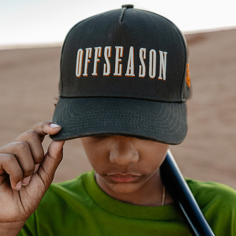 Person wearing a dark grey cap with 'OFFSEASON' text against a desert background