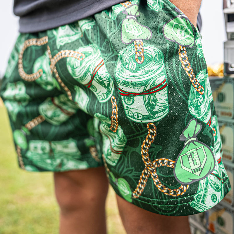 Person wearing green shorts with money and chain pattern outdoors.