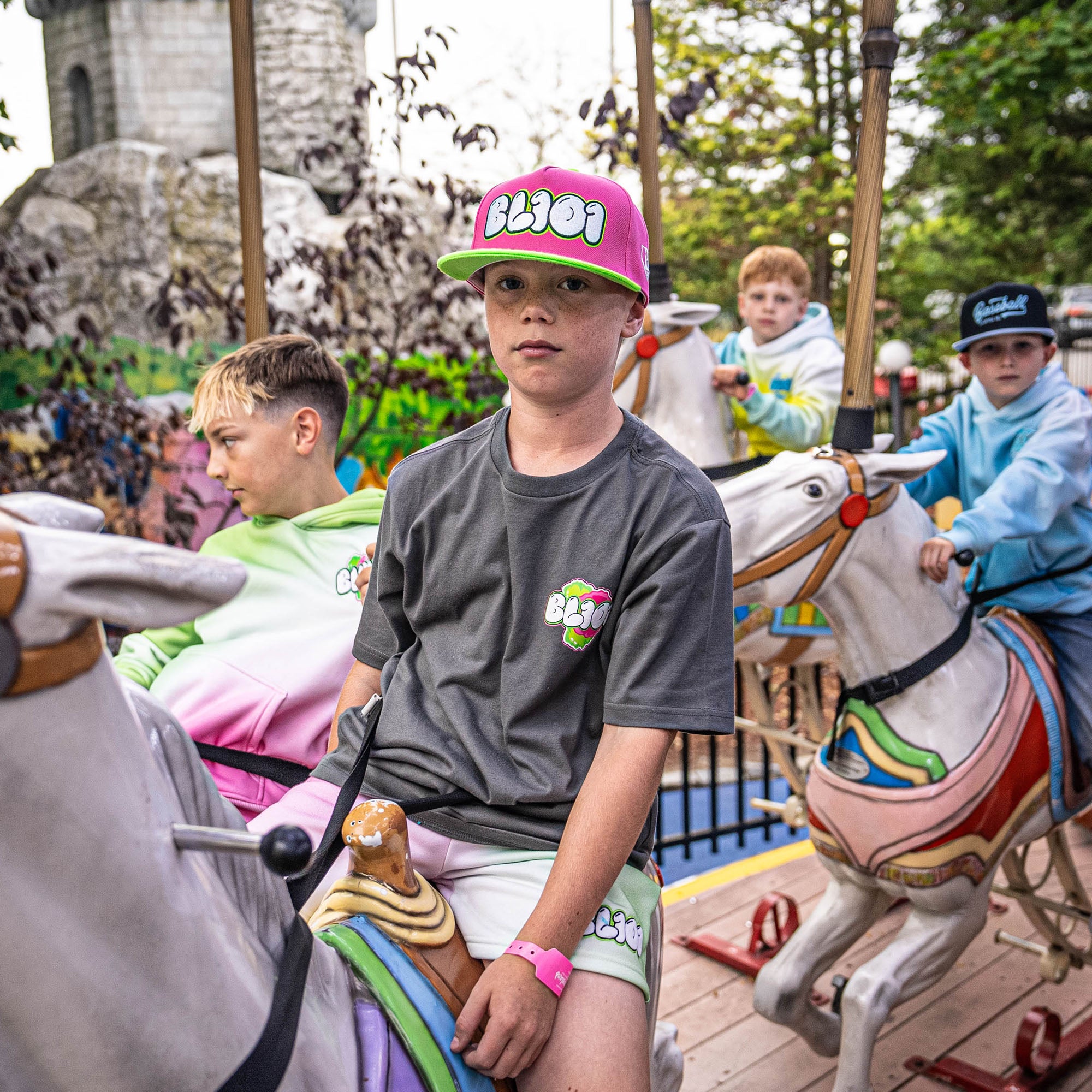 Children riding carousel horses with a castle-like structure in the background