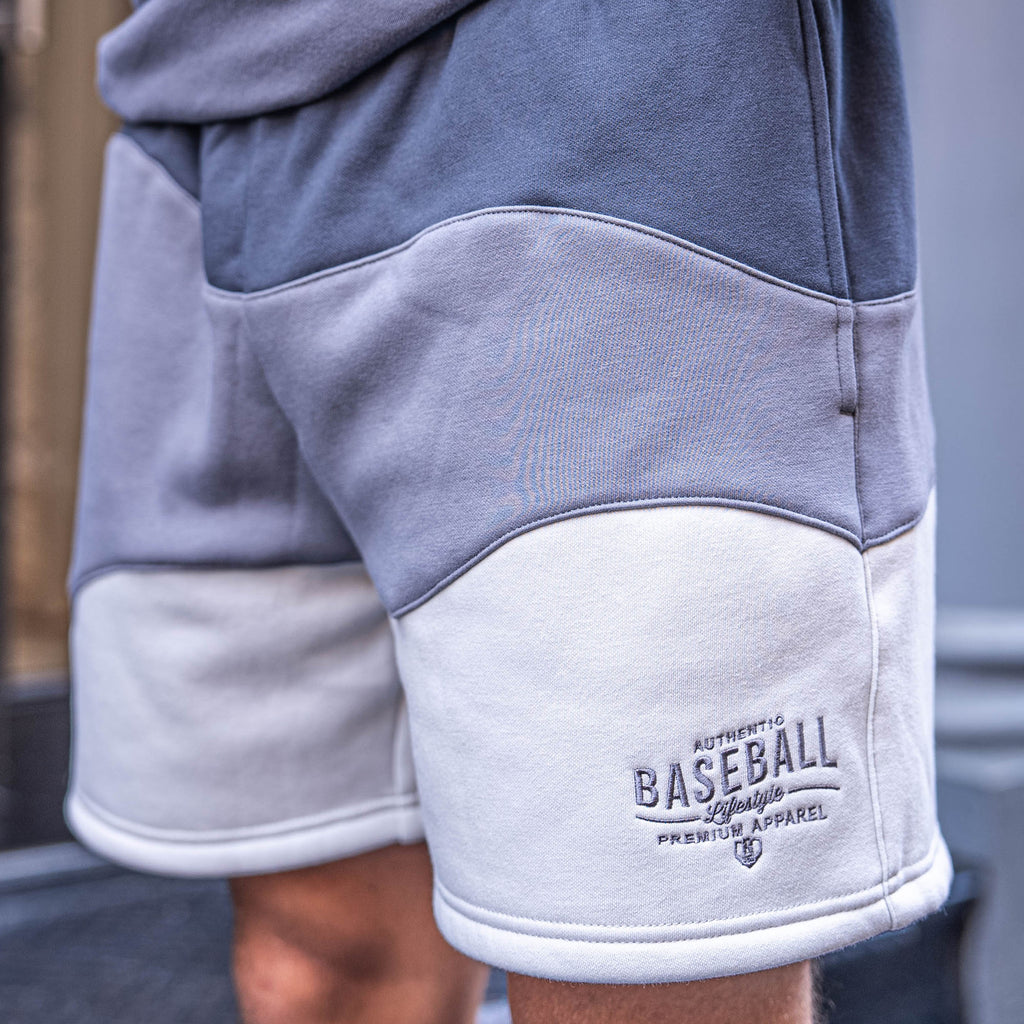 Gray and white shorts with 'Authentic Baseball Lifestyle Premium Apparel' logo on a blurred background