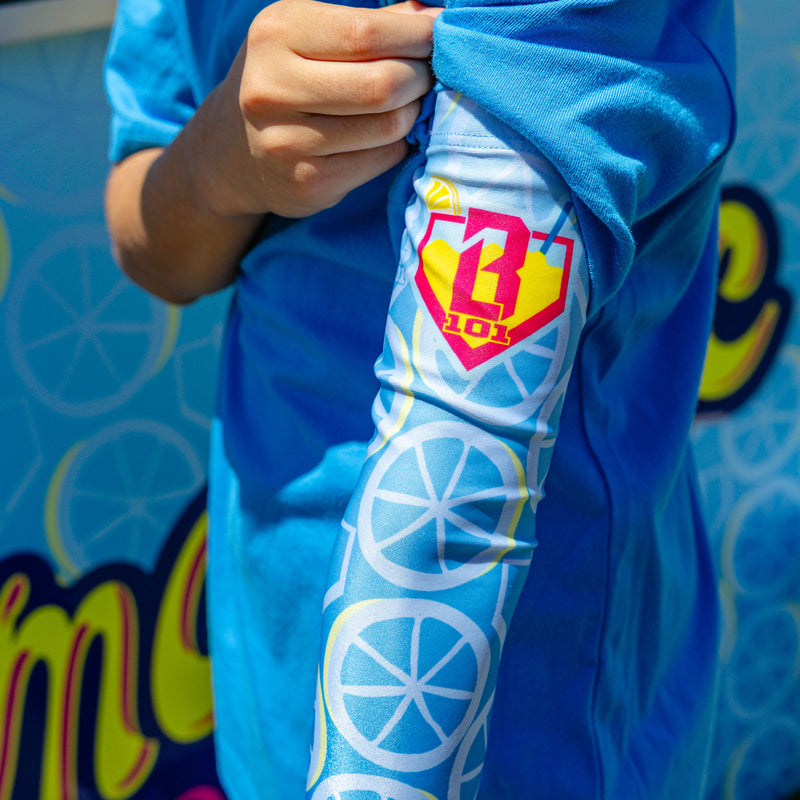 Youth model wearing blue youth arm sleeve with "Lemonade Splash" design
