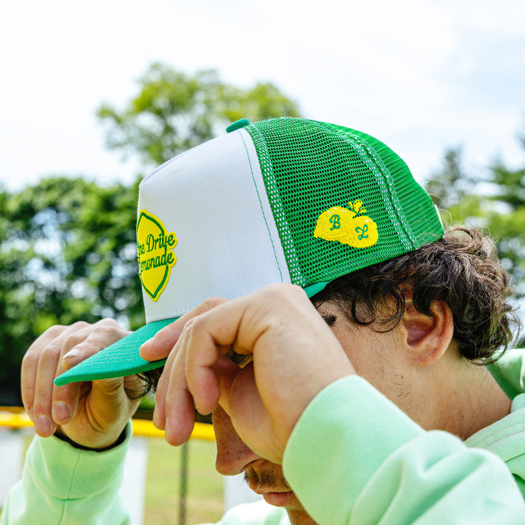 Adult model wearing green hat with "Line Drive Off Field" design
