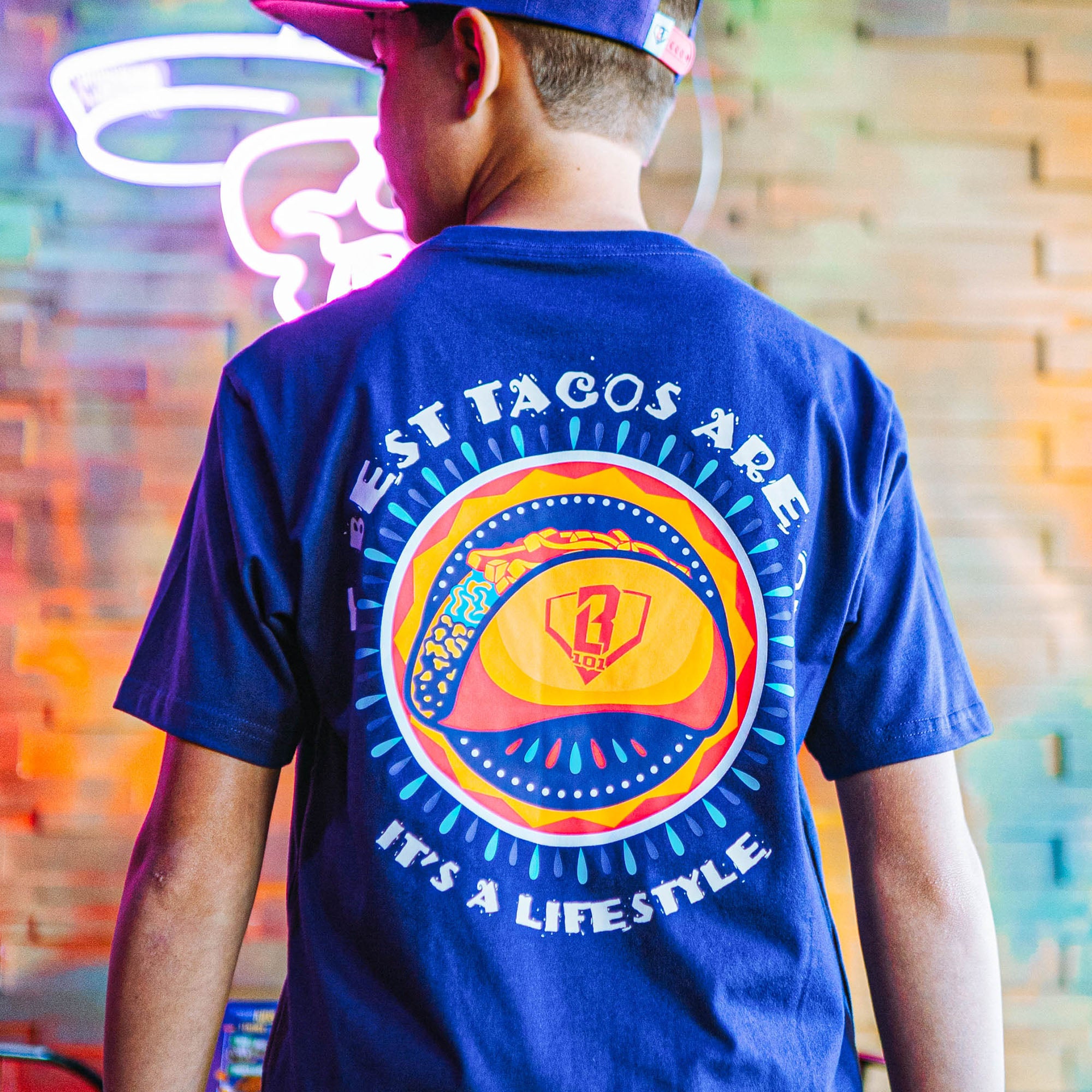 Purple t-shirt with colorful graphic and 'The Best Tacos Are Oppo It's a Lifestyle' text on a white background