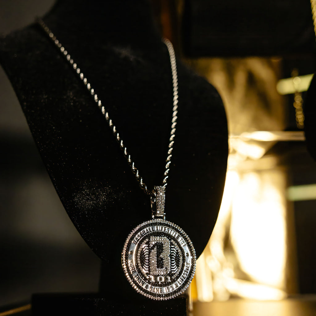 White Gold BL101 Medallion necklace hanging on a display stand against a black background