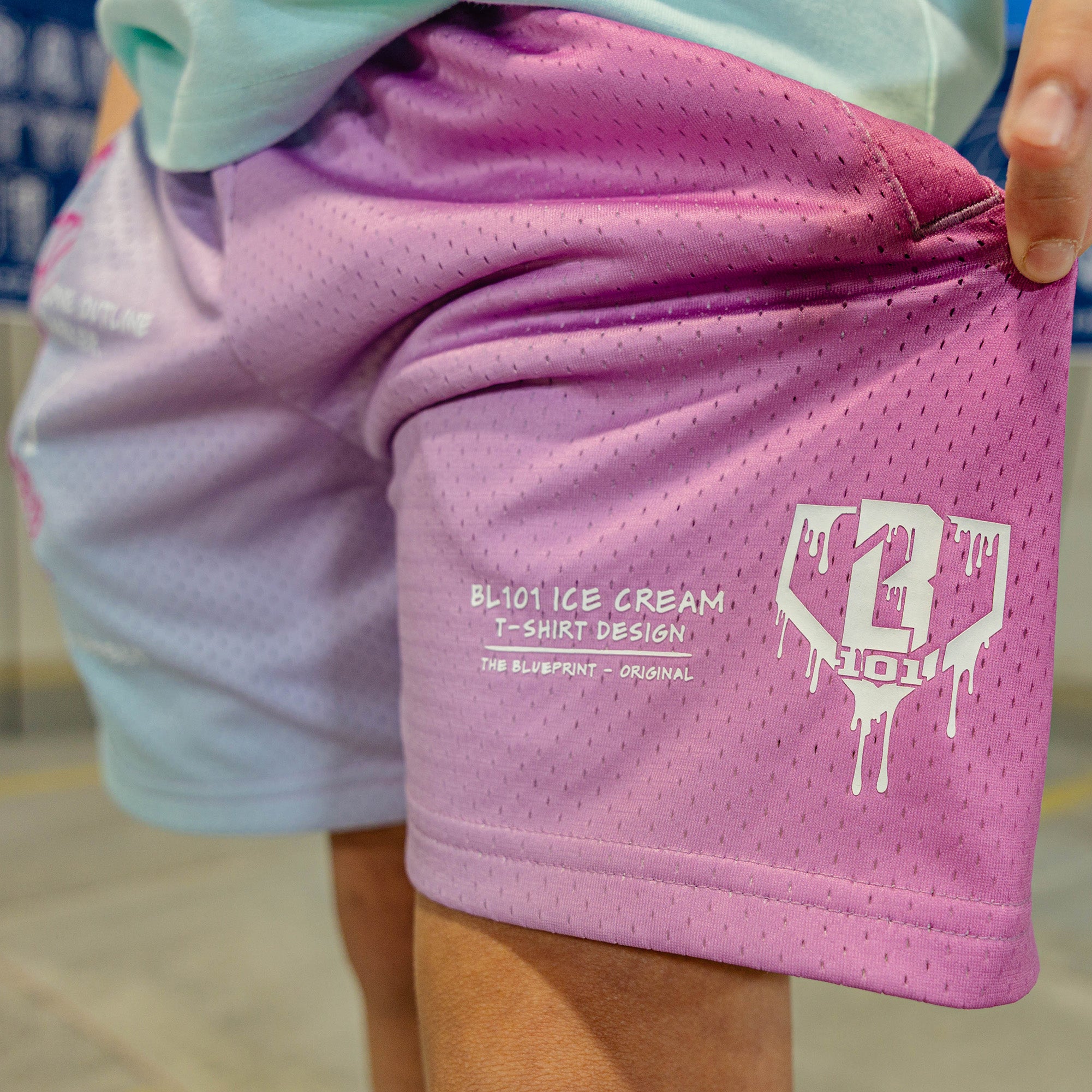 Pink-blue shorts with a BL101 logo and text on a person wearing a light green shirt.