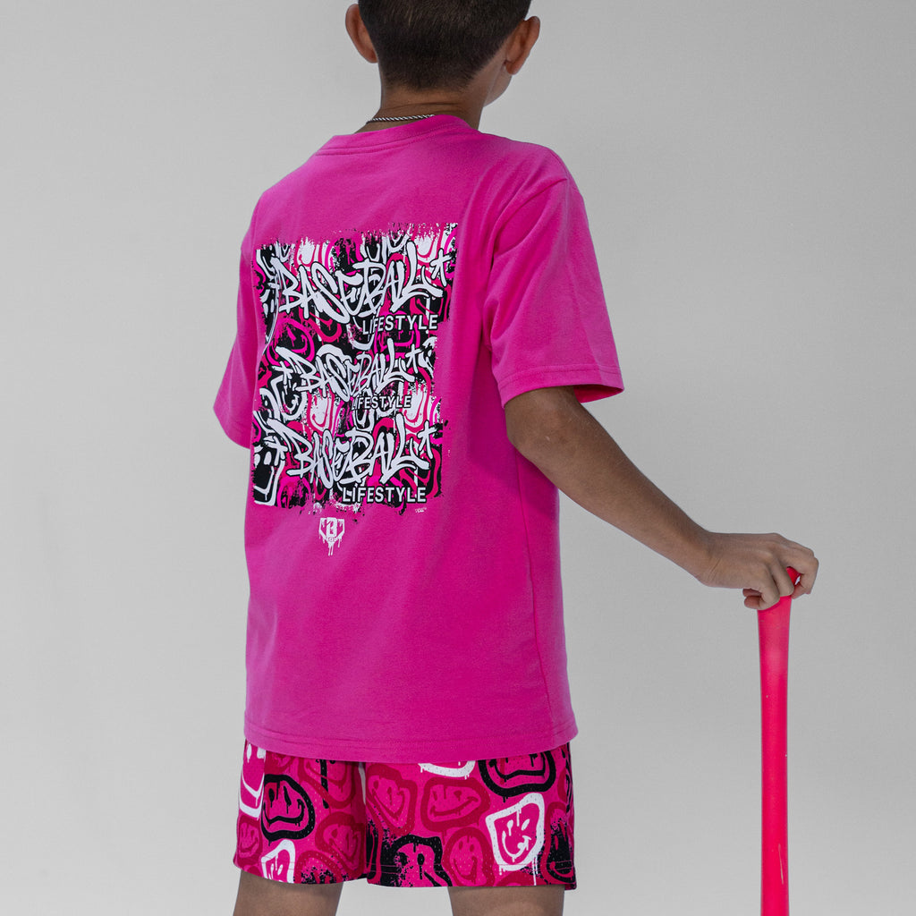 Person wearing pink shorts with black and white smiley graphics and a matching t- shirt, holding a baseball bat
