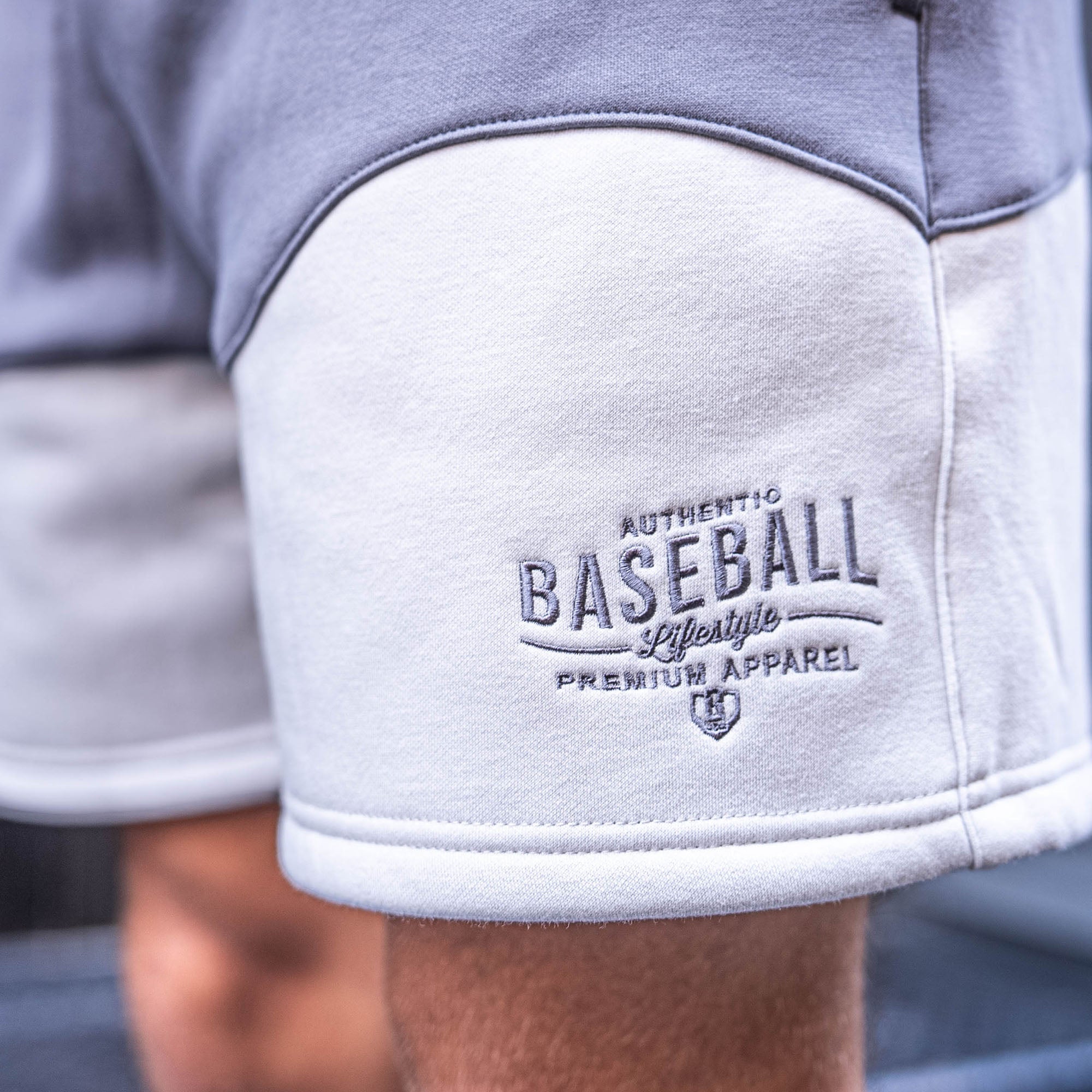 Gray and white shorts with 'Authentic Baseball Lifestyle Premium Apparel' embroidery on a blurred background