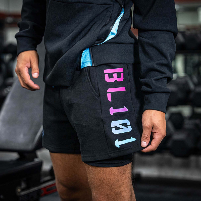Person wearing black shorts with colorful BL101 logo in a gym setting