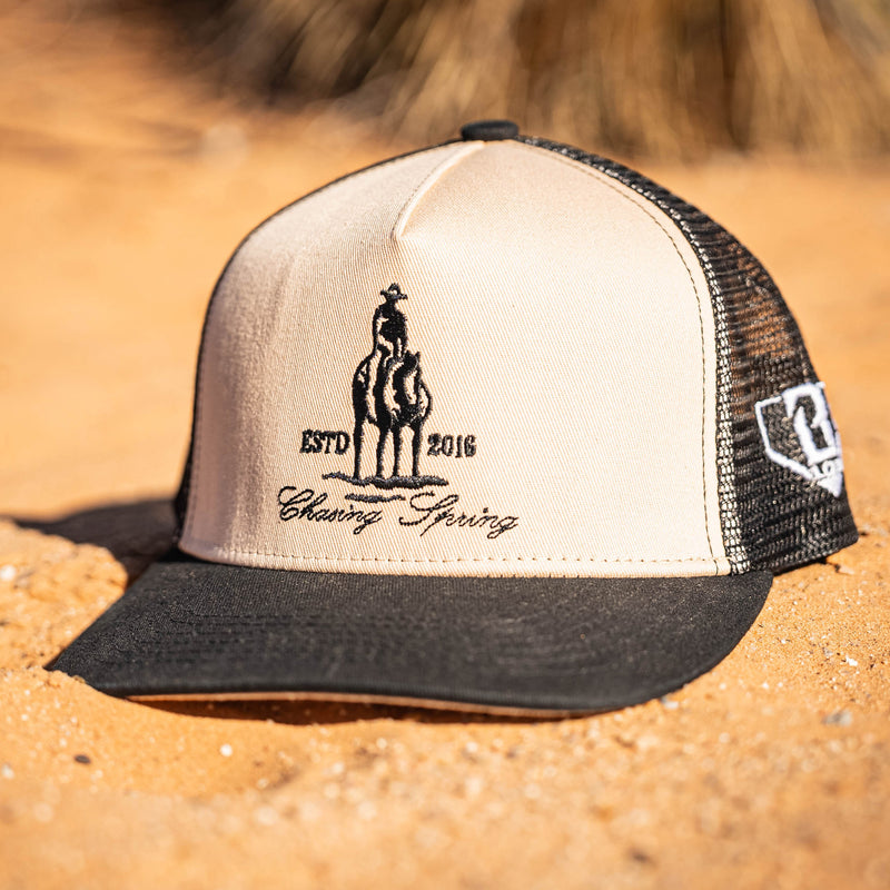 Beige and hat with a man on horse graphic and 'Chasing Spring' text on sandy surface