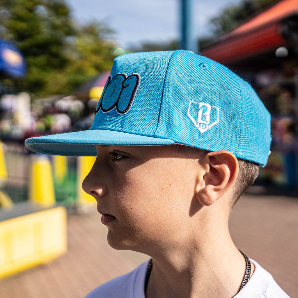 Person wearing a blue cap with a logo, outdoors with blurred background