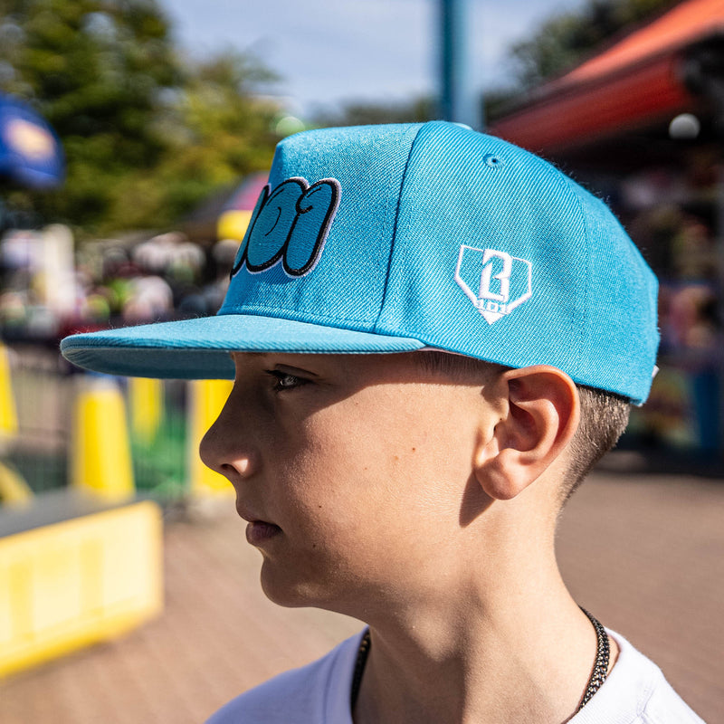 Person wearing a blue cap with a logo, outdoors with blurred background