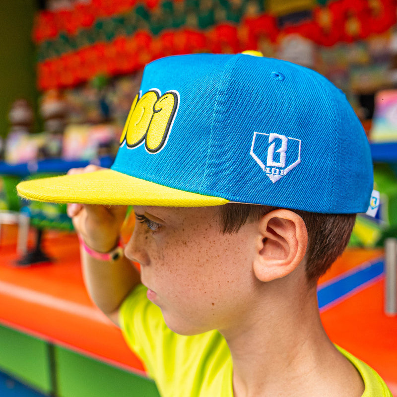 Child wearing a blue and yellow cap with white BL101 logo