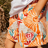 Person wearing a colorful cactus and desert patterned shorts with a logo on a blurred natural background
