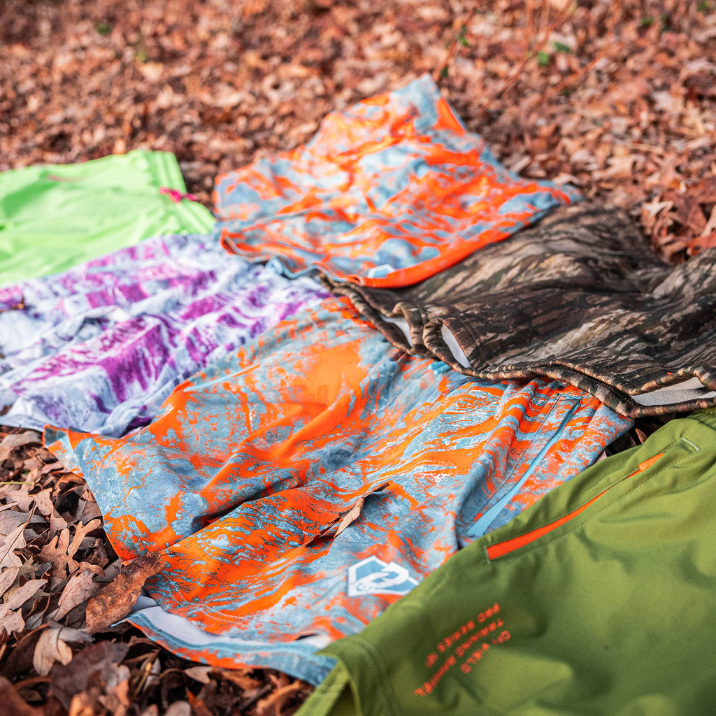 Green, cammo, purple, orange and blue shorts on a leafy ground.