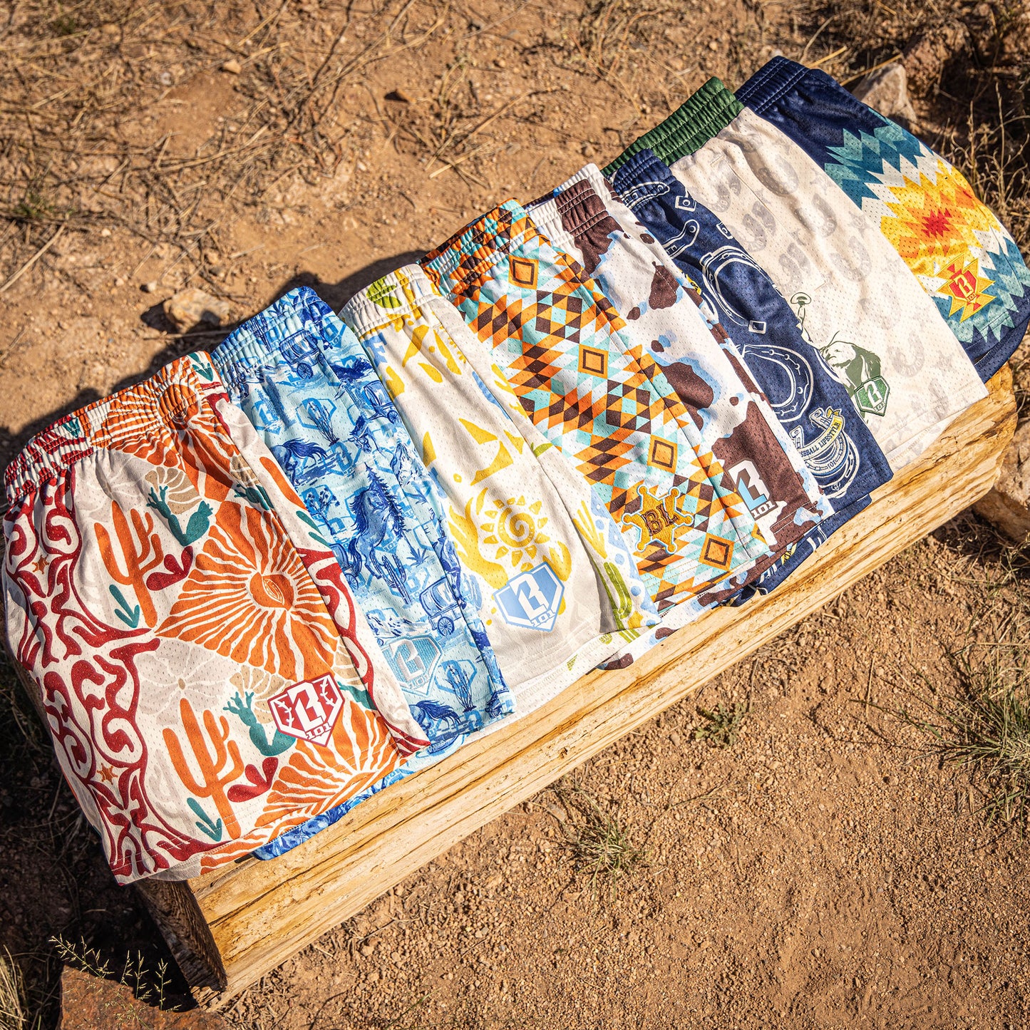 Seven pairs of patterned shorts on a wooden block against a natural background
