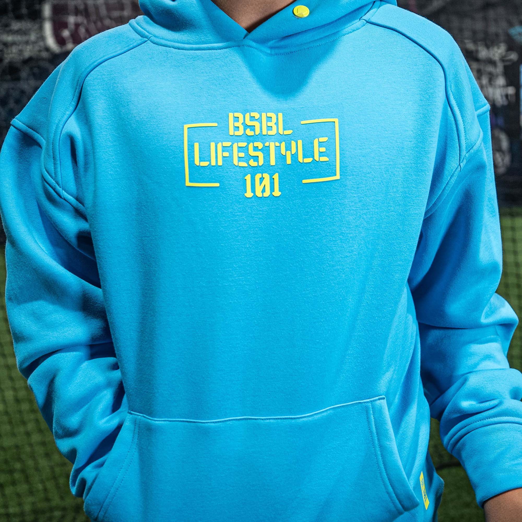 Blue hoodie with yellow 'BSBL LIFESTYLE 101' text on a blurred background