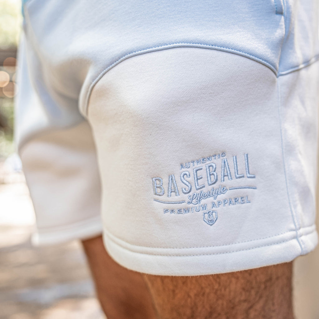 White and blue baseball shorts with 'Authentic Baseball Lifestyle Premium Apparel' text on a blurred background