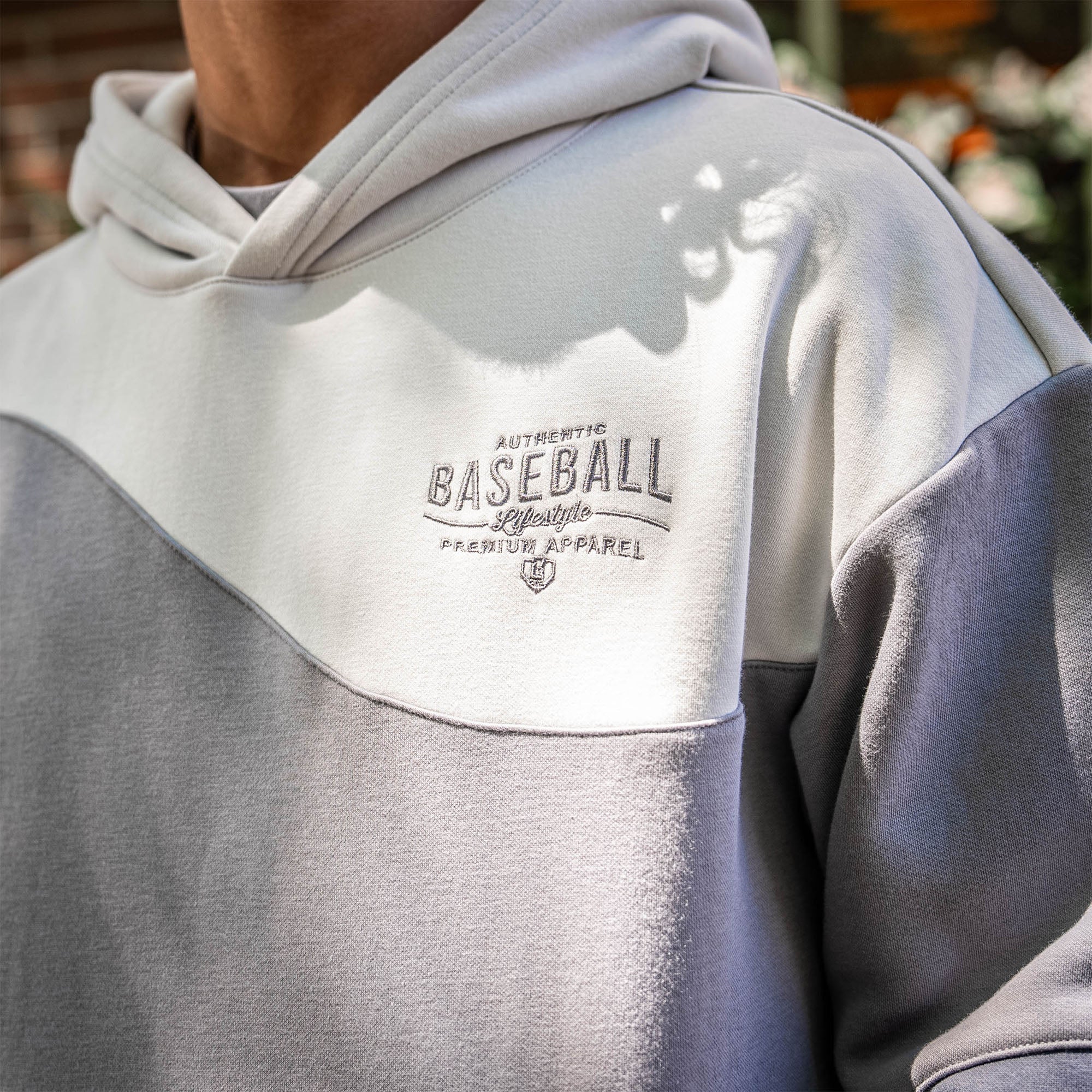 Close up of gray hoodie with 'Authentic Baseball Lifestyle PREMIUM APPAREL' logo