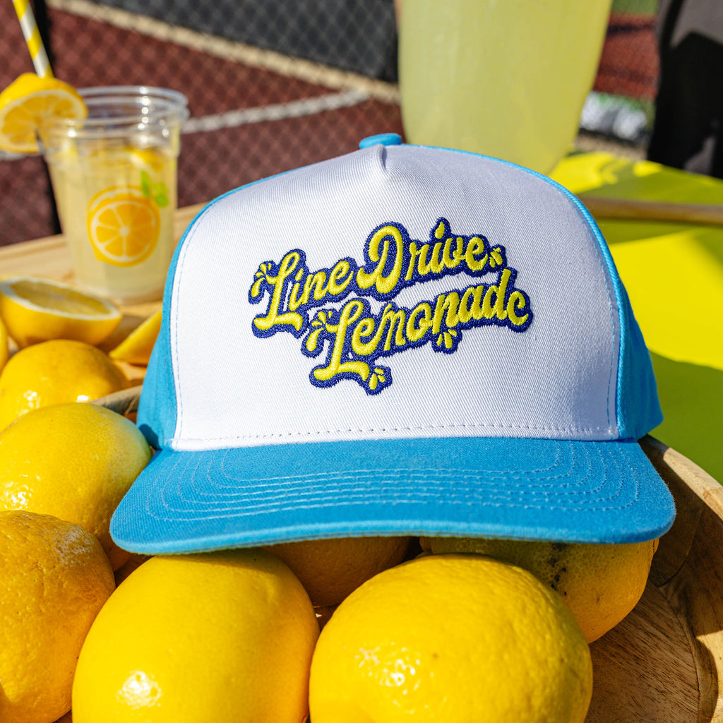 Adult model wearing blue hat with "Lemonade Off Field" design