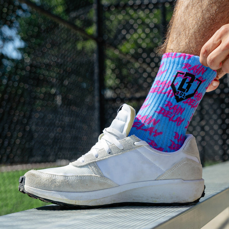 Adult model wearing multi-color socks with "Rain Delay Performance  3-Pack" design