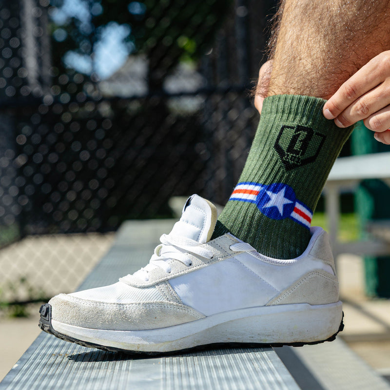 Adult model wearing green socks with "Warhawk Performance  3-Pack" design