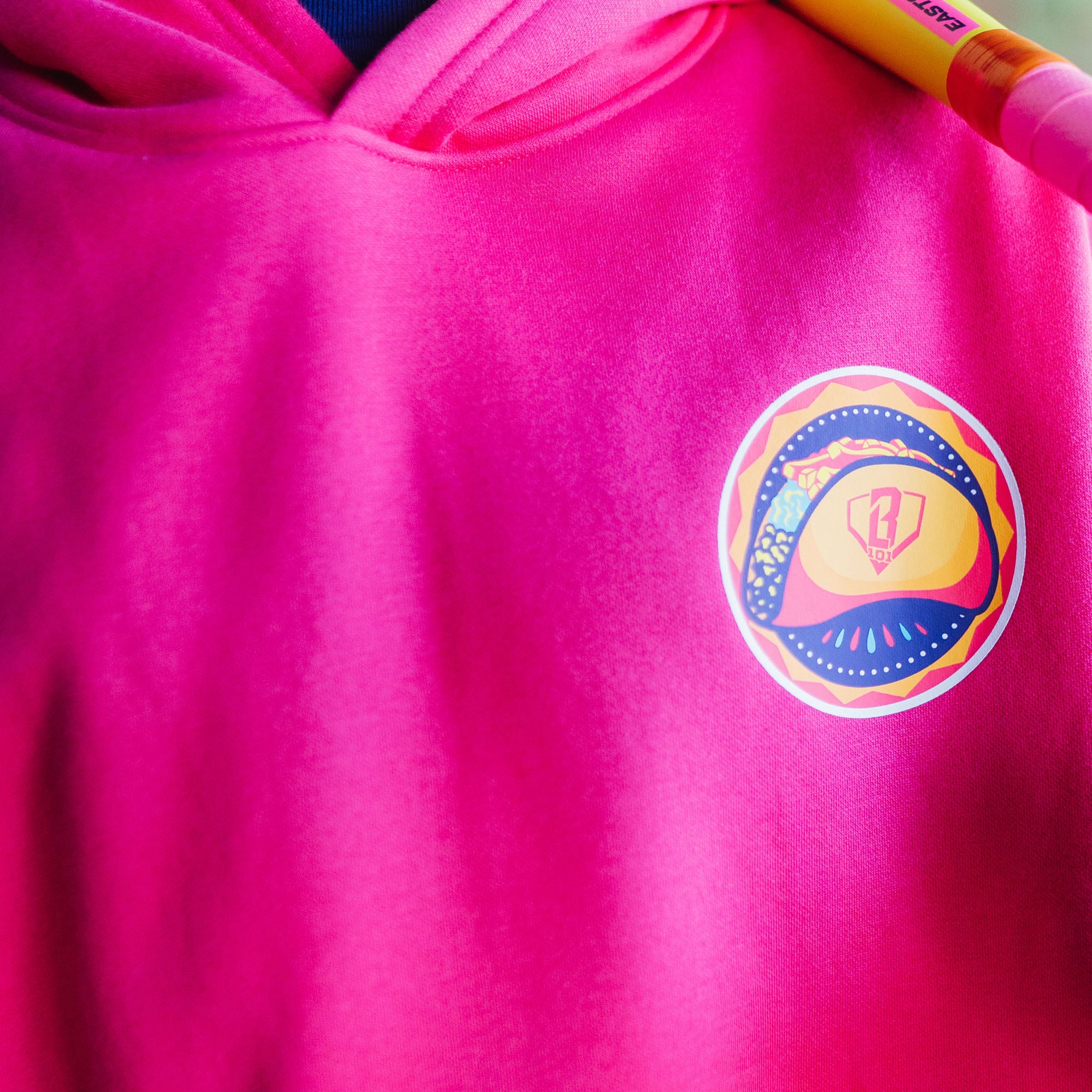 Pink hoodie with a colorful taco logo on the chest