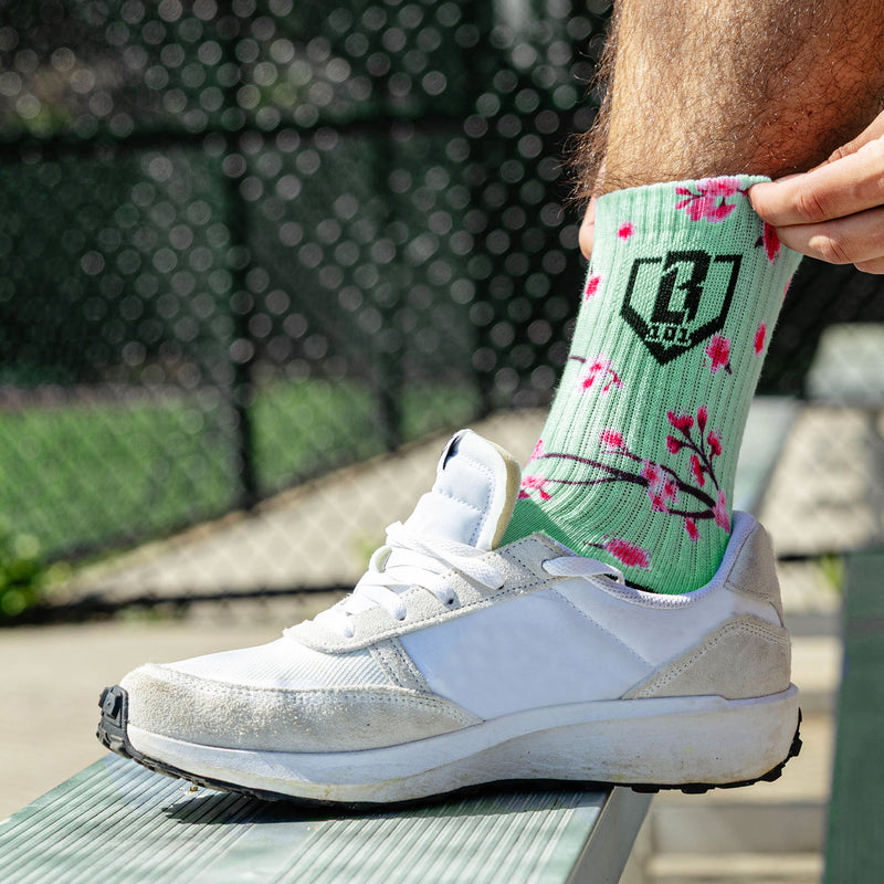 Adult model wearing multi-color socks with "Cherry Blossoms Performance  3-Pack" design