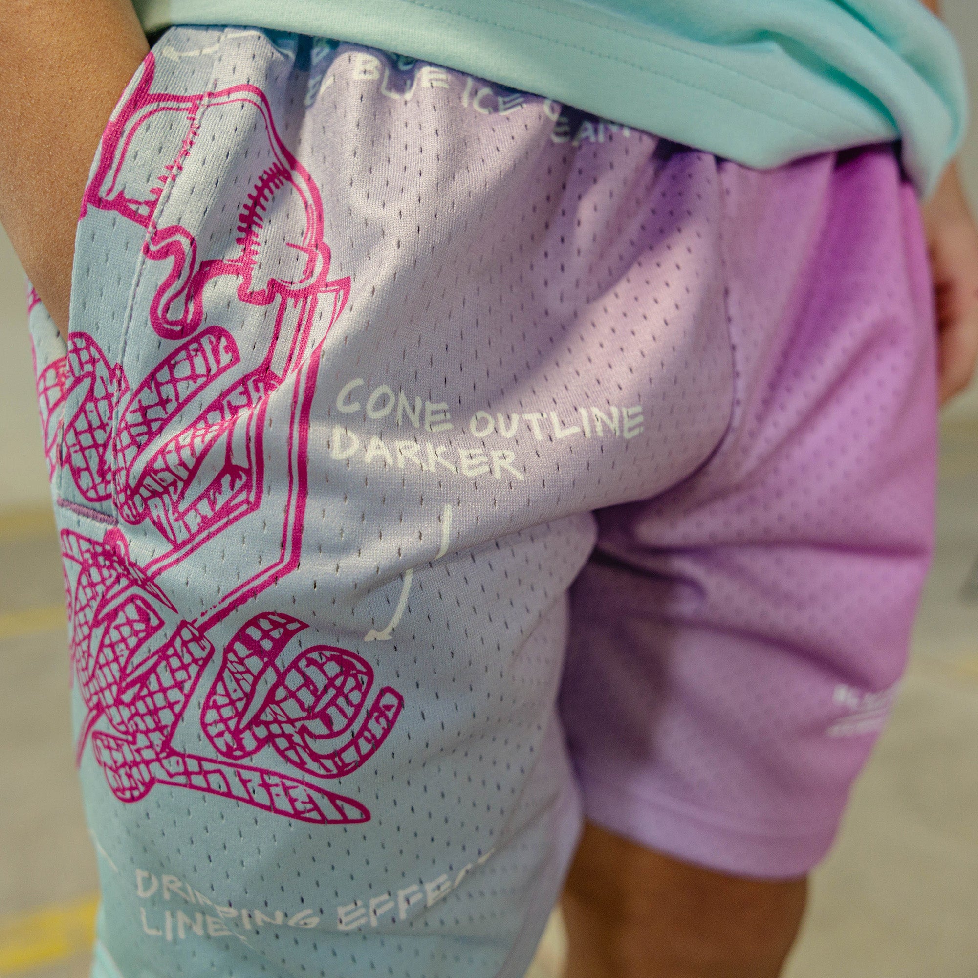 Pink-blue shorts with a BL101 logo and text on a person wearing a light green shirt.