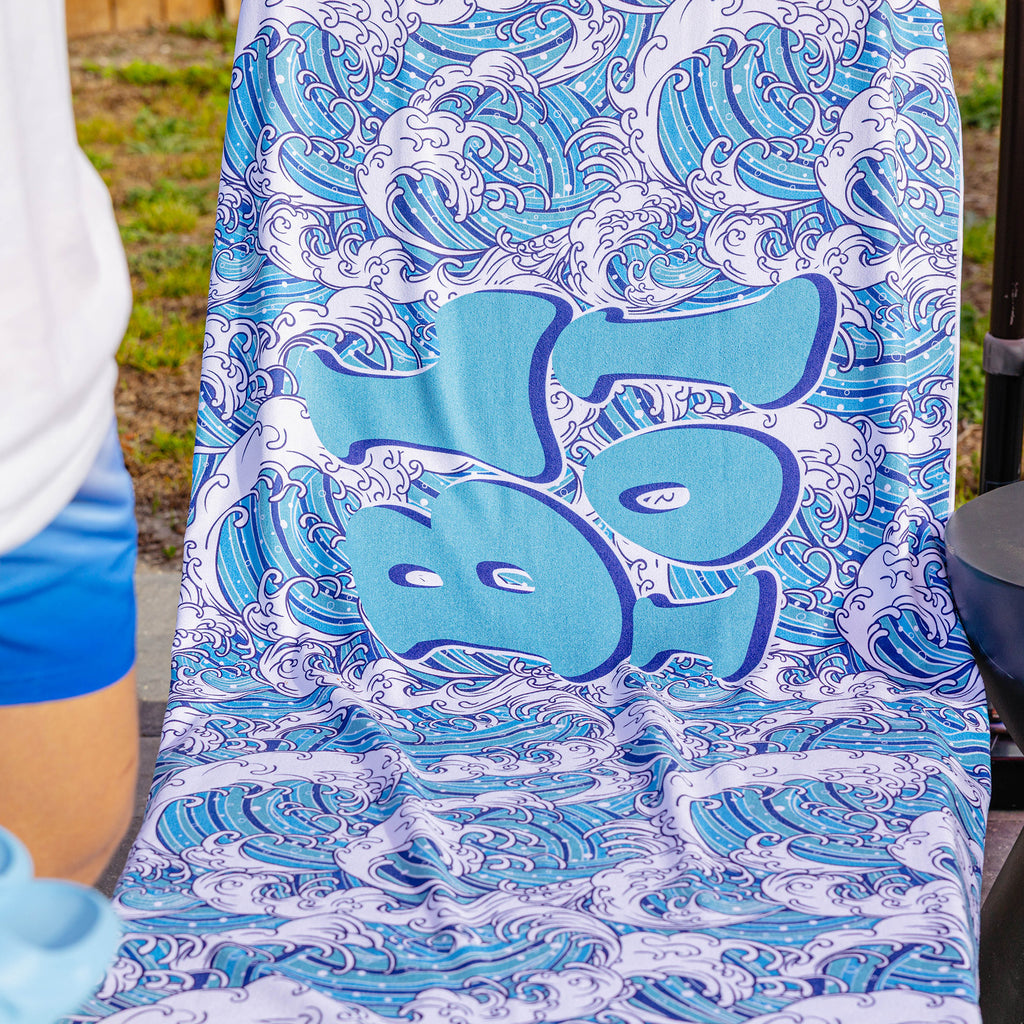 Close-up of BL101 wave-print beach towel with large graffiti-style BL101 logo over a wave pattern.