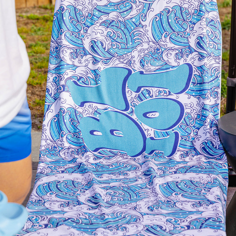 Close-up of BL101 wave-print beach towel with large graffiti-style BL101 logo over a wave pattern.