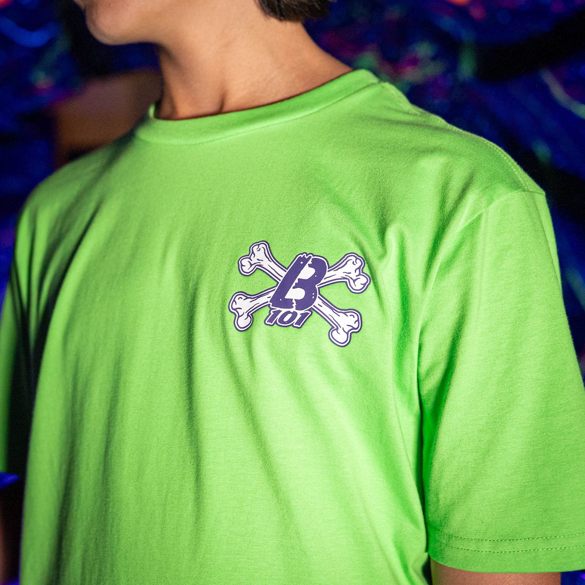 Adult model wearing green Crossbones graphic tee