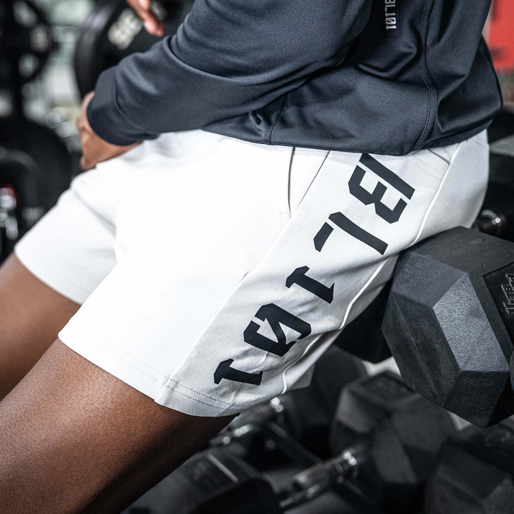 Person sitting on weights white shorts with black BL101 text on a white background