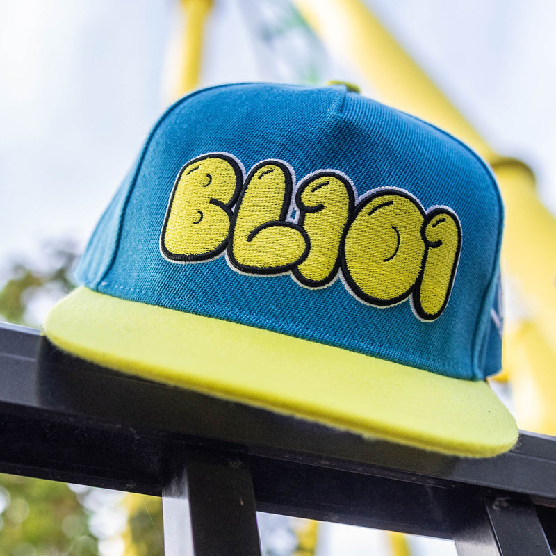 Blue and yellow cap with 'BL101' logo on a blurred background
