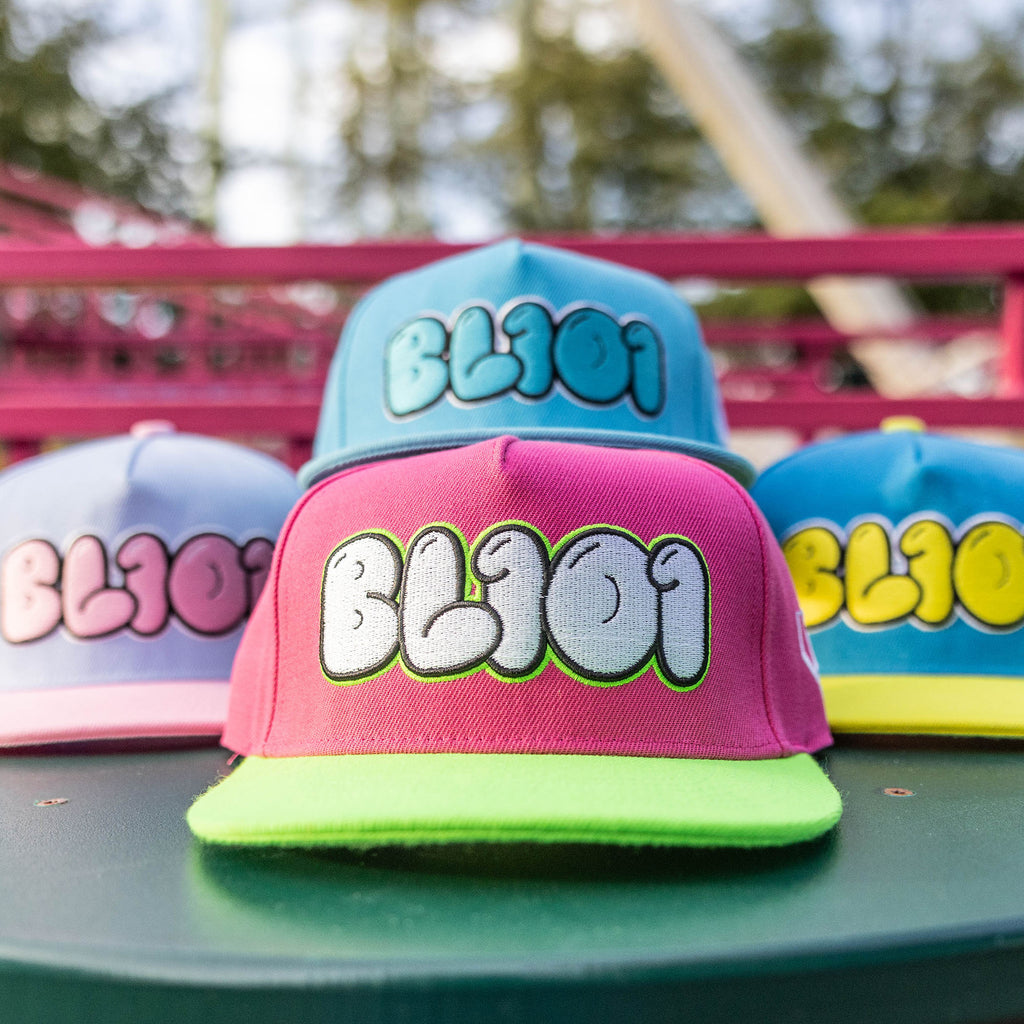 Colorful caps with 'BL101' text on a green surface with a blurred background